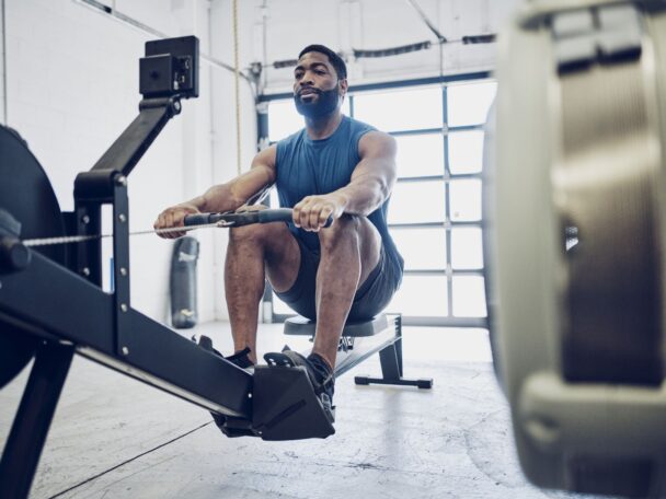 A man exercises on a rowing machine, demonstrating proper form and technique in a fitness environment. - Fitsse