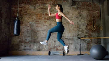 A woman leaps joyfully in a gym, showcasing her energy and enthusiasm for fitness. - Fitsse