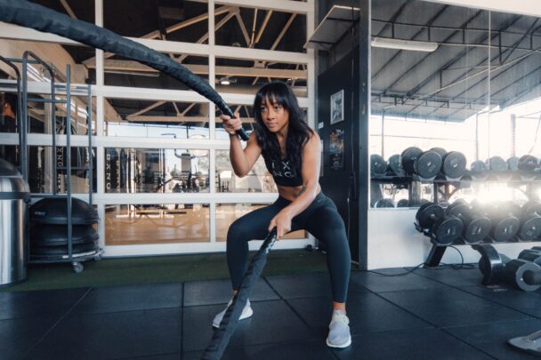 A woman performs a pull-up at the gym, showcasing strength and determination in her workout routine. - Fitsse