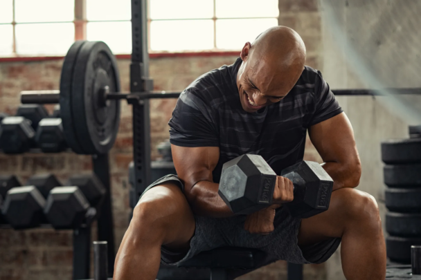 A man performs a squat while holding a dumbbell, showcasing strength and proper form in a gym setting. - Fitsse