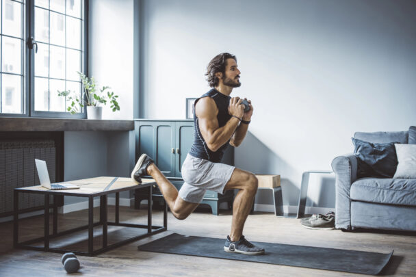 A man performs a workout in his living room, showcasing determination and fitness in a home environment. - Fitsse