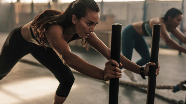 Two women performing push-ups in a gym, showcasing strength and teamwork in their workout routine. - Fitsse