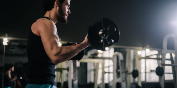 A man lifting weights in a gym, showcasing strength and determination during his workout session. - Fitsse