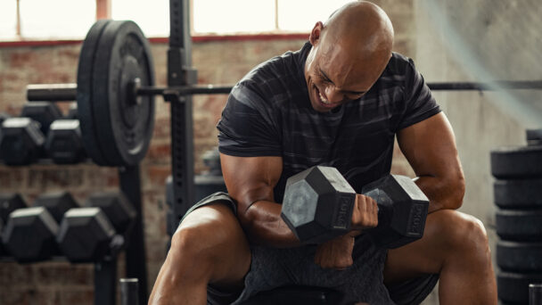 A man lifting weights in a gym, showcasing strength and determination during his workout session. - Fitsse