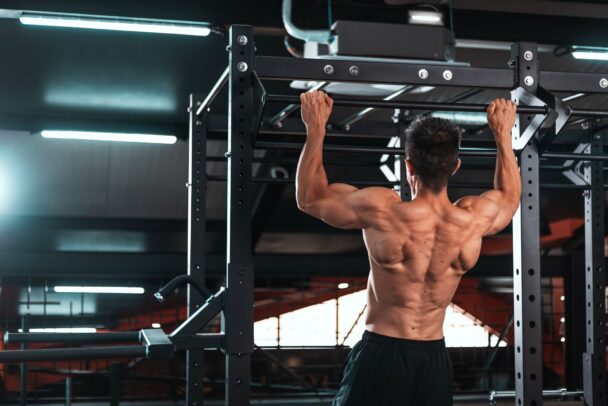 A man performs pull-ups on a bar, showcasing strength and determination in his workout routine. - Fitsse