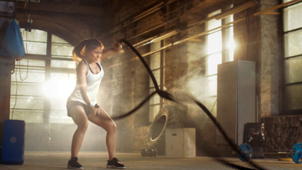 A woman performs a workout routine in a rustic, old building, showcasing strength and determination amidst historical architecture. - Fitsse