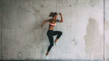 A woman in a sports bra and leggings leaps into the air, showcasing her athleticism and energy during a workout. - Fitsse