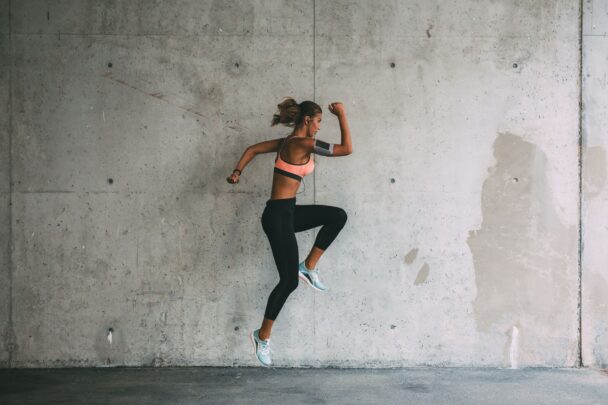 A woman in a sports bra and leggings leaps into the air, showcasing her athleticism and energy during a workout. - Fitsse